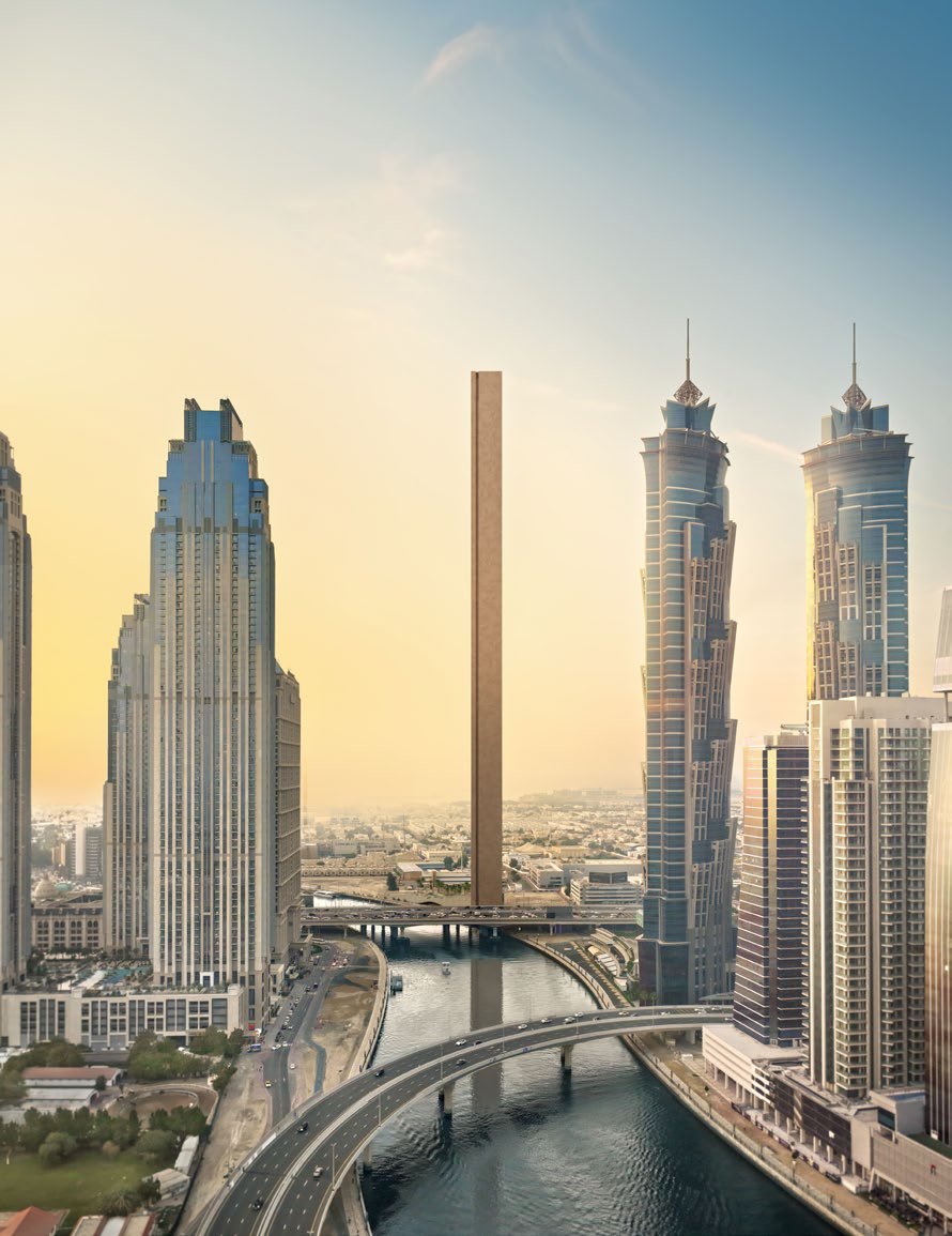 Aerial of the slim tower rising beside the Dubai Water Canal and skyscrapers