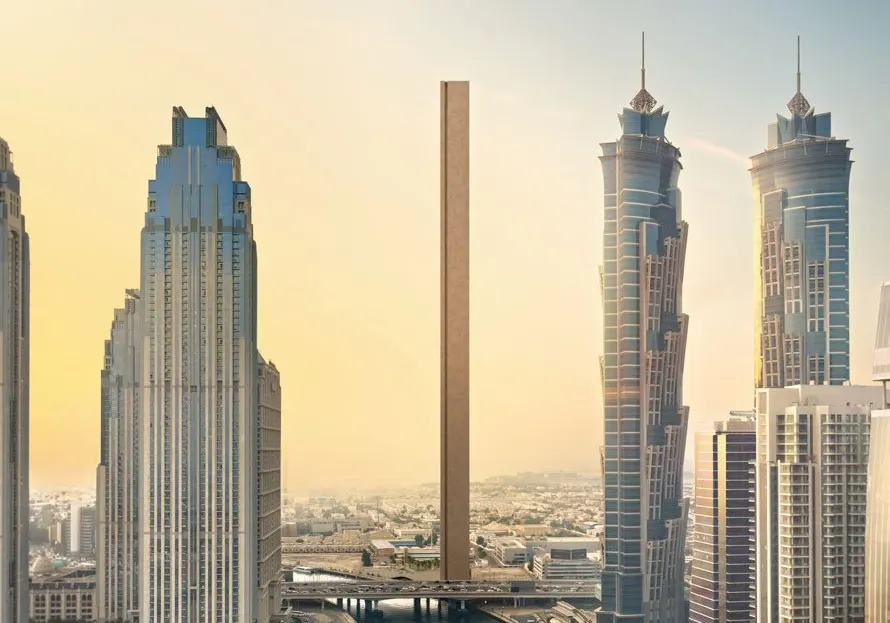 Aerial of the slim tower rising beside the Dubai Water Canal and skyscrapers